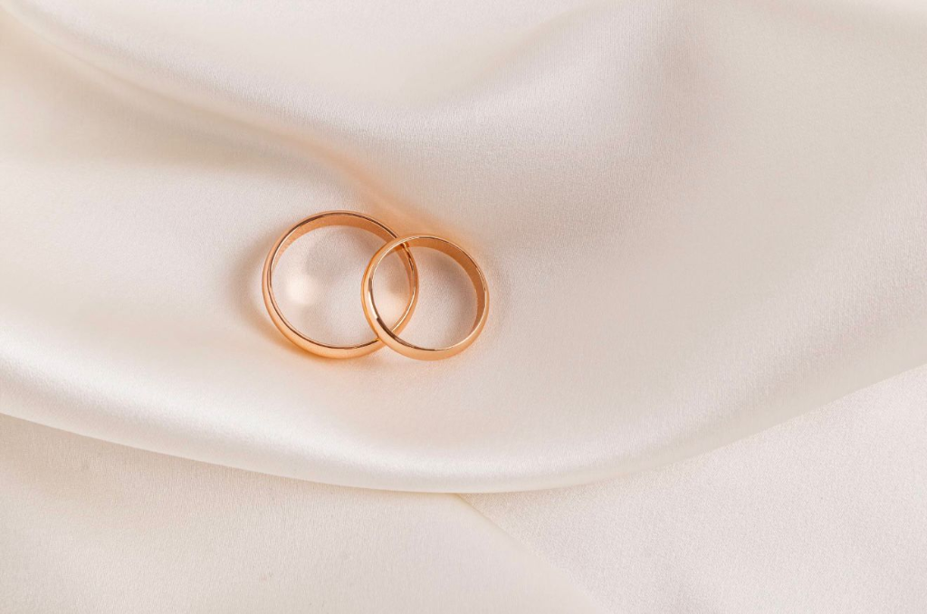 Elegant wedding rings on white silk background